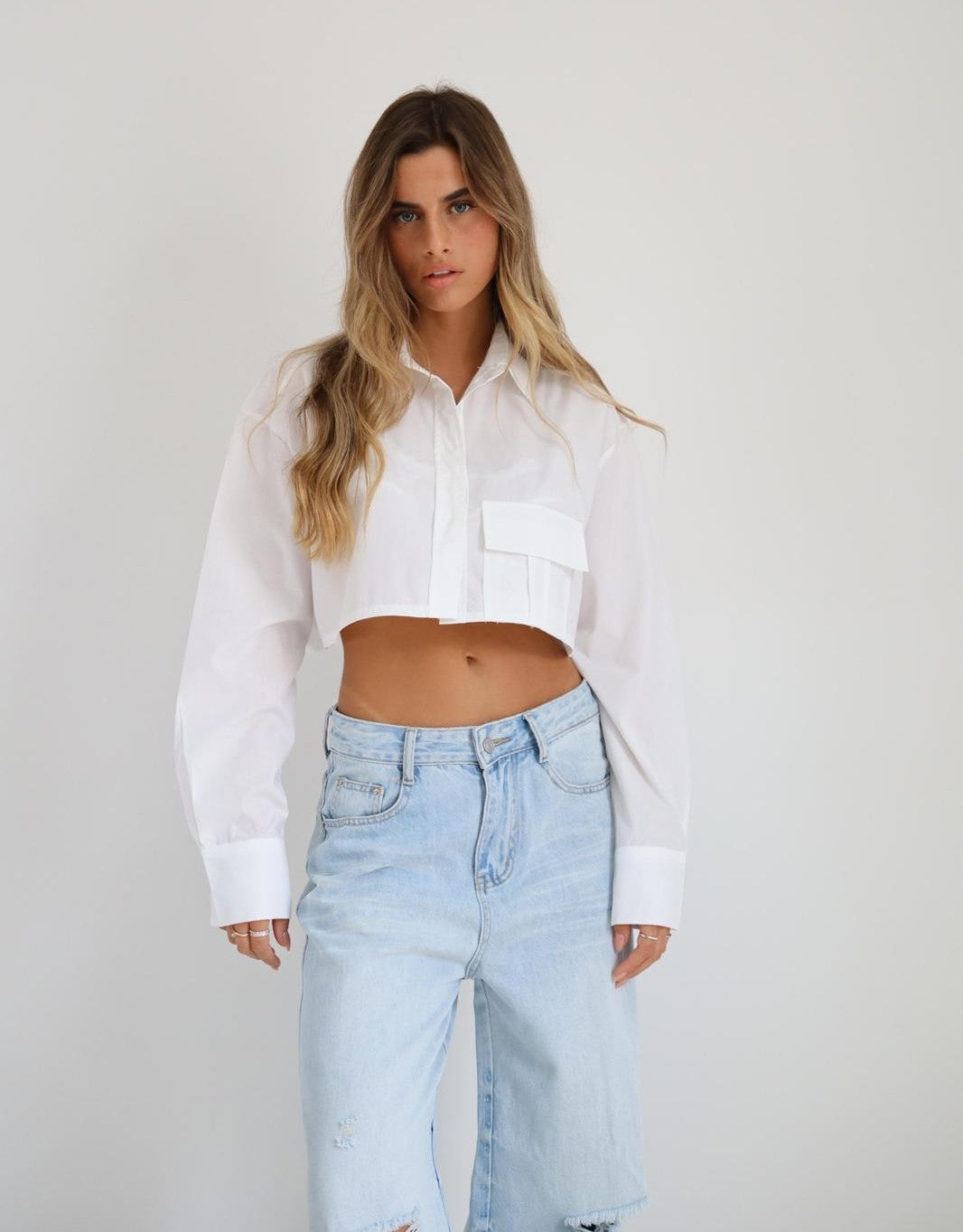 חולצת Mor לבנה בגזרת קרופ מכופתרת עם צווארון קלאסי וכיס קדמי בשילוב ג׳ינס בהיר