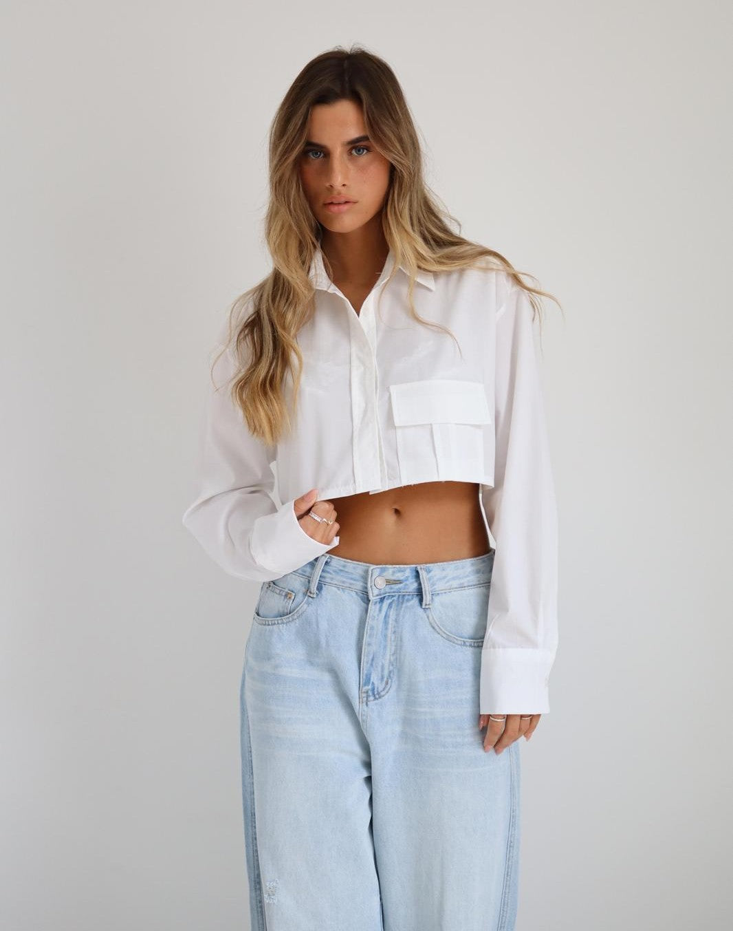 חולצת Mor לבנה בגזרת קרופ מכופתרת עם צווארון קלאסי וכיס קדמי בשילוב ג׳ינס בהיר