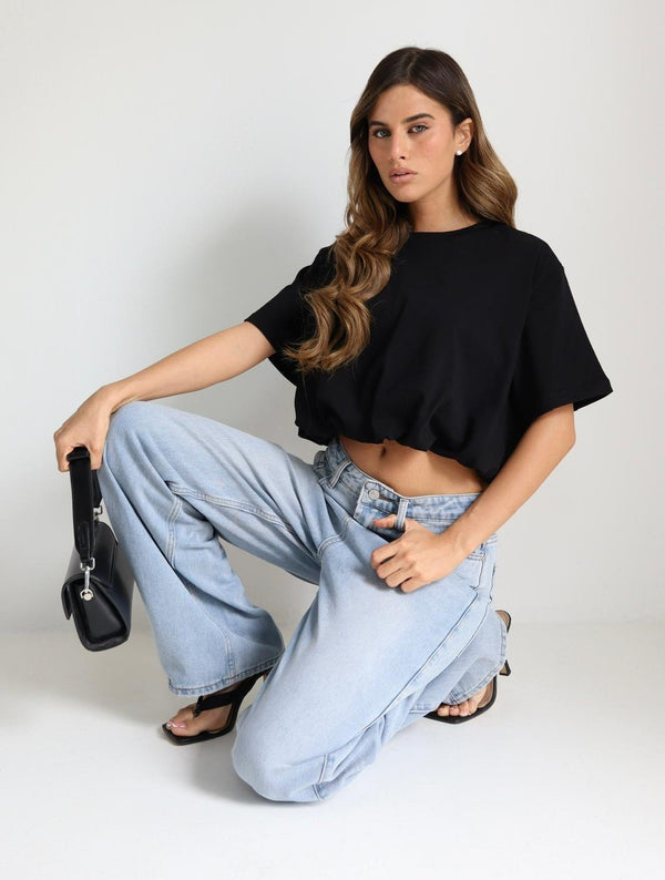 דוגמנית לובשת חולצת Beli בצבע שחור בגזרת קרופ עם ג׳ינס בהיר